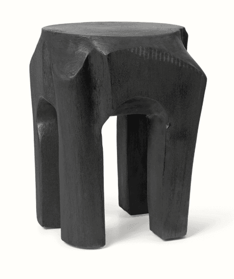 A dark-colored, solid wood stool with a sculptural, organic form. It features a flat circular top and four integrated, splayed legs with carved, irregular surfaces, finished in a deep black hue. — 3D model