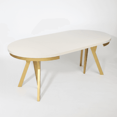 An oval-shaped dining table with a cream-colored top and a metallic gold base. The table top appears to be segmented, suggesting it might be extendable. The base consists of two angled, V-shaped legs that meet in the center, providing a modern and somewhat sculptural aesthetic. — 3D model