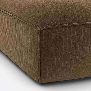 A modular armchair with a low profile and a geometric design. The upholstery features a corduroy-like texture with vertical ribbing. The seat is a rounded pentagonal shape, and the backrest is straight and slightly curved to form a corner unit. The frame appears to be upholstered, with visible piping along the seams. — 3D model