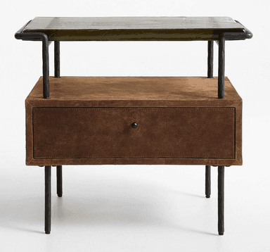 A nightstand featuring a distressed brown leather-wrapped body with a single drawer, supported by a black industrial-style metal frame and legs. The top surface is an olive green, textured material, possibly stone or a stone-look composite, which sits within the metal frame. An open shelf is present above the drawer. — 3D model