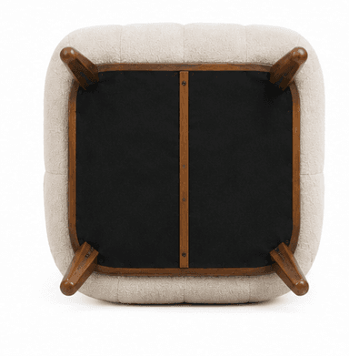An upholstered armchair featuring a plush, rounded silhouette. The chair is covered in a textured cream-colored boucle fabric. It has integrated, softly curved arms and a continuous backrest. The seat base includes subtle vertical channel tufting. The chair rests on short, splayed dark wood legs. A matching rectangular lumbar pillow is included. — 3D model