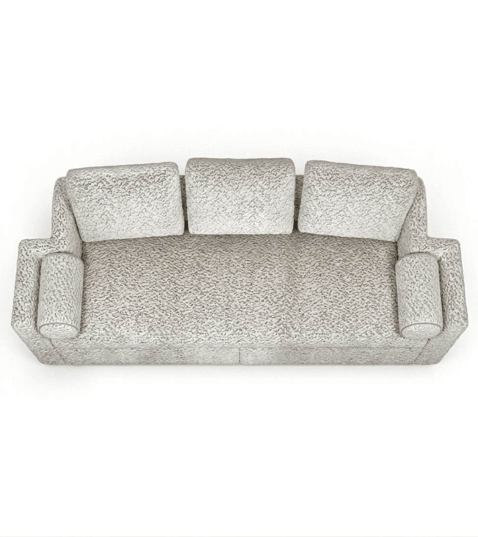 A contemporary three-seater sofa upholstered in a light, neutral-toned, richly textured fabric. It features three loose back cushions, wide integrated armrests, and two cylindrical bolster pillows at each end. The sofa has a low-profile design with a deep, continuous seat cushion. — 3D model