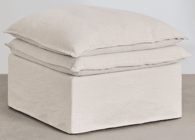A light beige, square, slipcovered ottoman featuring a boxy base and two stacked, plush cushions on top, presenting a soft and inviting appearance. — 3D model