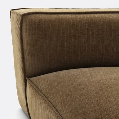 A modular armchair with a low profile and a geometric design. The upholstery features a corduroy-like texture with vertical ribbing. The seat is a rounded pentagonal shape, and the backrest is straight and slightly curved to form a corner unit. The frame appears to be upholstered, with visible piping along the seams. — 3D model