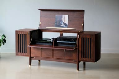 A long, low, dark wooden cabinet with a distinct mid-century modern design. It features slatted sections on the curved ends, a central open shelf, and multiple drawers and cabinet doors below, all adorned with small brass pull handles. The cabinet is supported by angled, tapered legs with brass ferrules at the bottom. — 3D model
