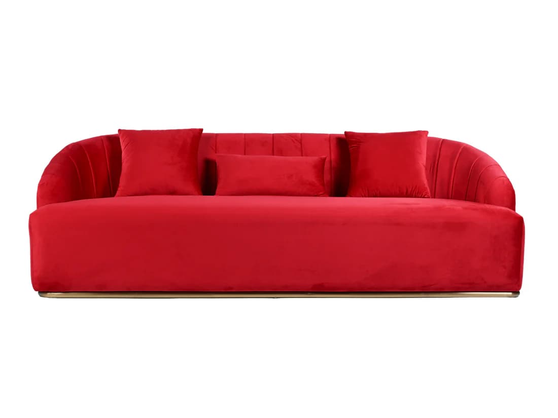 A modern red velvet sofa with a curved back and armrests. The back features vertical channeling, and it comes with three throw pillows: two square and one rectangular. The sofa is elevated by a thin, polished metallic base. — 3D model