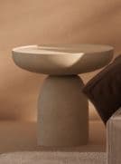 A contemporary side table featuring a monolithic, sculptural design. It has a round top with a slightly recessed edge, supported by a sturdy, cylindrical pedestal base, all in a uniform matte beige finish. — 3D model