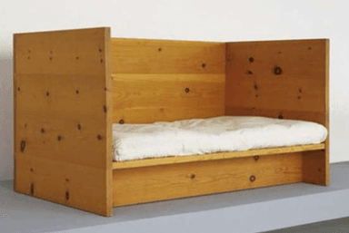 A minimalist daybed crafted from light-colored pine wood, featuring a simple three-sided enclosure. The design showcases visible wood grain and knots, indicative of natural timber. It includes a white mattress resting on a recessed platform, suitable for a compact sleeping or lounging solution. — 3D model