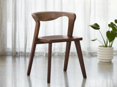 A modern dining chair constructed entirely from wood, featuring a curved backrest that flows seamlessly into the seat. The chair has four tapered legs, providing a sturdy base. The overall design is minimalist and organic. — 3D model