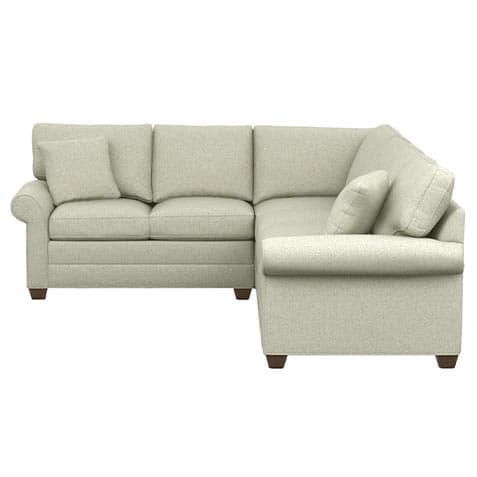 An L-shaped sectional sofa featuring a light, textured fabric upholstery. The design includes classic rolled arms on both ends and multiple plush back and seat cushions, along with additional throw pillows for comfort. The sofa is supported by short, dark wooden tapered feet. — 3D model