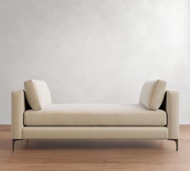 A contemporary upholstered daybed with integrated armrests at both ends, featuring a flat seating surface and two loose bolster cushions for back support, all resting on slender metal legs. — 3D model