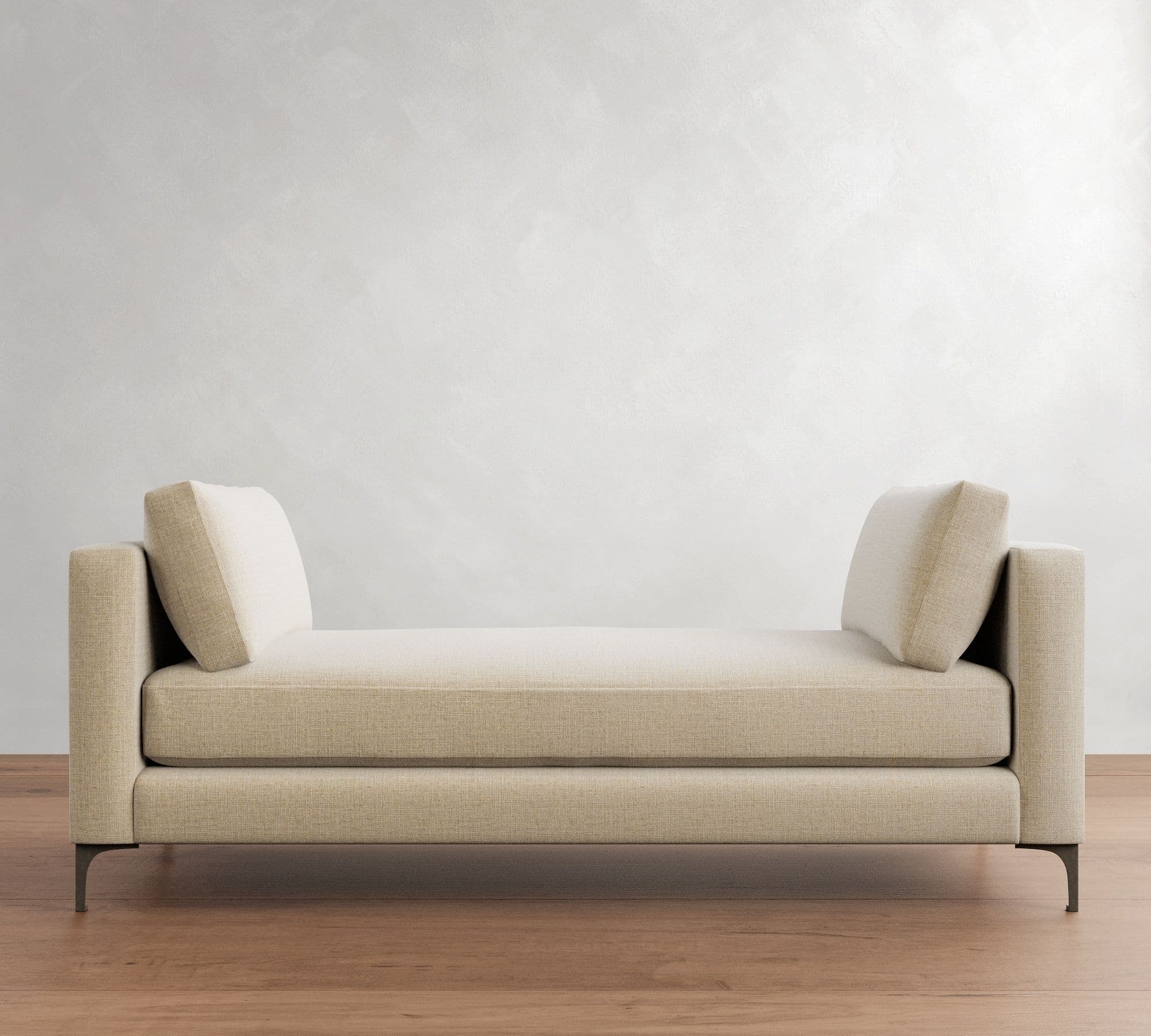 A contemporary upholstered daybed with integrated armrests at both ends, featuring a flat seating surface and two loose bolster cushions for back support, all resting on slender metal legs. — 3D model