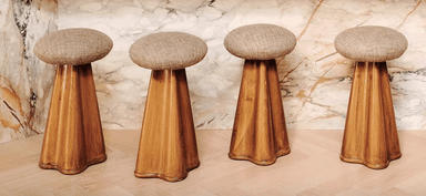 A stool with a round upholstered seat and a flared wooden base. The base has a textured wood grain pattern and curves inward towards the bottom, ending in a subtly scalloped edge. — 3D model