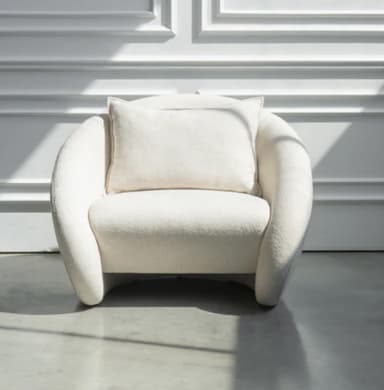 A contemporary lounge chair with a rounded, organic silhouette, fully upholstered in a textured, off-white fabric, and featuring a loose back cushion. — 3D model