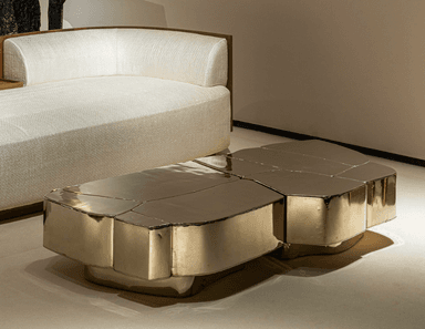 A modern, irregularly shaped coffee table constructed from multiple geometric segments that fit together like a puzzle. The surface has a textured, almost faceted appearance, with rounded edges on the side panels and a slightly elevated base. — 3D model