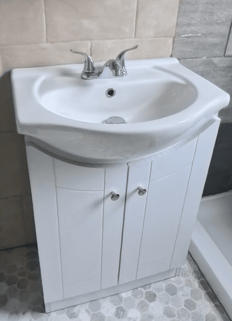 A freestanding bathroom vanity unit featuring a white ceramic basin integrated into a white cabinet with two doors. The basin has a single faucet hole and a chrome faucet. The cabinet doors have a shaker-style panel design and are fitted with round chrome knobs. The base of the unit has a subtle plinth. — 3D model