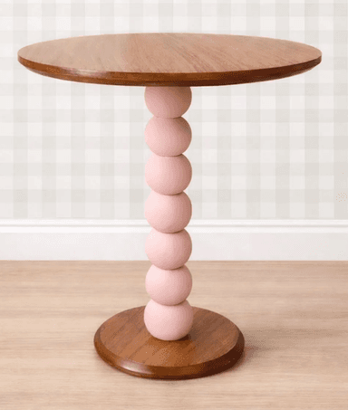 A modern round side table featuring a distinct spherical pedestal base. The circular tabletop and the matching round base are finished in a natural wood tone with visible grain. The central pedestal is composed of five stacked, graduated spheres painted a soft pink color, providing a striking two-tone contrast to the wood elements. — 3D model
