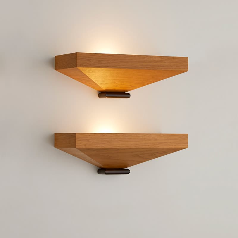 A contemporary wall sconce featuring a distinctive triangular design. The outer frame is constructed from light-toned wood, likely oak, with prominent grain, and houses an internal diffuser panel that emits a warm, soft light. The sconce is mounted to the wall via a compact, dark-finished metal base positioned at the bottom point of the triangle. Its sharp angles and material combination give it a modern and minimalist aesthetic. — 3D model