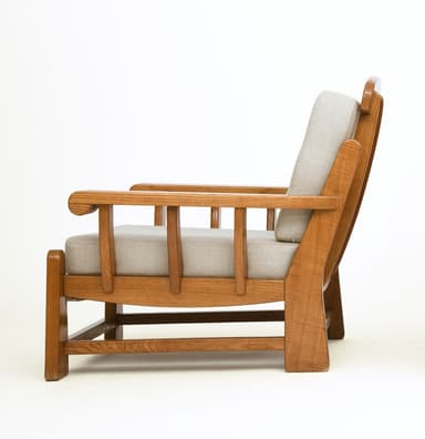 A sturdy, craftsman-style lounge chair featuring a solid oak wood frame and thick, upholstered cushions. The chair has broad, rounded arms, slatted side panels, and block legs. The back cushion is button-tufted. — 3D model