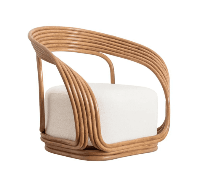 This is a contemporary armchair featuring a distinctive frame crafted from multiple curved rattan rods, creating a fluid, sculptural silhouette for the back and armrests. The seat is a plush, square-shaped cushion upholstered in a light-colored, textured bouclé fabric. The rattan frame extends around the base, providing stability and a cohesive design. The chair appears to be a single seating unit, designed for comfort and aesthetic appeal. — 3D model