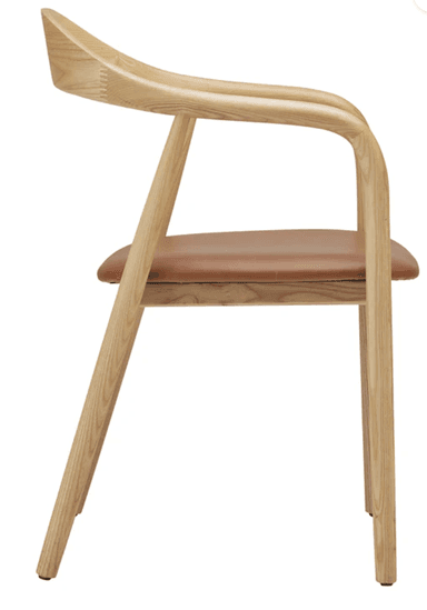 A Scandinavian modern armchair constructed from light-colored ash wood with a subtly visible grain. It features a continuous, gently curved element that forms both the backrest and the armrests, creating a fluid silhouette. The seat is a flat, padded cushion upholstered in a cognac-colored leather or faux leather. The frame is supported by four round, slightly tapered legs, connected by simple stretchers beneath the seat. — 3D model