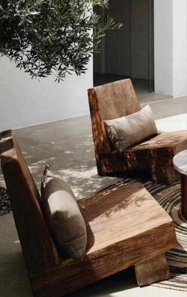 A modern armchair with a solid, blocky construction. It features a low profile with a thick seat and a reclined backrest. A rectangular lumbar pillow is placed against the backrest. The overall design is minimalist and appears to be crafted from solid wood. — 3D model