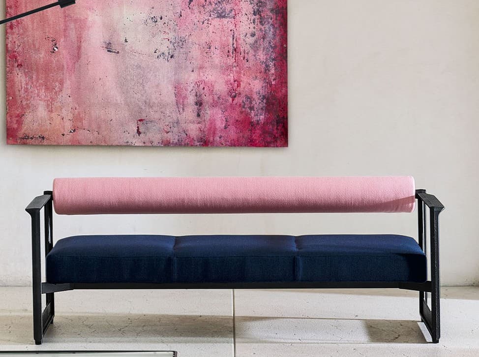 A modern bench featuring a minimalist black metal frame with dark blue upholstered seat cushions and a contrasting pink cylindrical bolster serving as the backrest. The frame includes integrated armrests. — 3D model