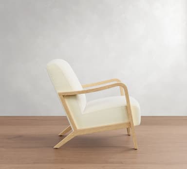 A modern armchair with a light-colored upholstered seat, back, and armrests, supported by a light wood frame. The frame consists of four legs, with the front legs extending upwards to form the armrests, and a connecting horizontal piece. — 3D model