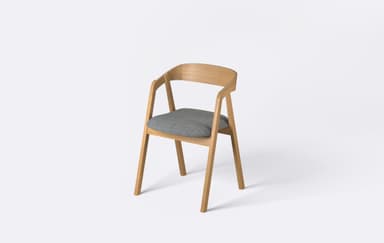 A modern dining armchair featuring a light-toned wooden frame and a grey upholstered seat. The backrest is crafted from bentwood, forming a continuous curve that extends into integrated armrests. The chair is presented against a plain white background, highlighting its clean lines and minimalist design. — 3D model