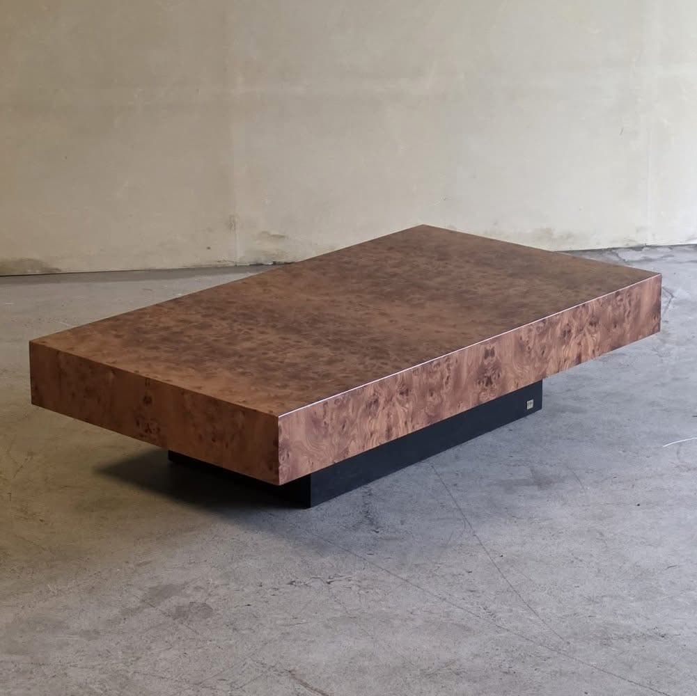 A rectangular coffee table with a burl wood veneer top and a dark, solid base. The burl wood pattern is characterized by its swirling, organic grain and rich brown tones. The base appears to be a contrasting solid material, possibly wood or metal, with a matte finish. The table has a low profile and a modern, sophisticated aesthetic. — 3D model