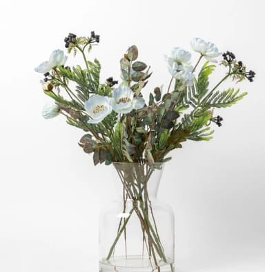 A clear glass vase containing an artificial floral arrangement. The arrangement features white poppy-like flowers, dark green fern fronds, eucalyptus leaves with reddish hues, and clusters of small dark berries. The vase has a fluted neck and a sturdy, rounded base, allowing the stems of the artificial plants to be visible through the transparent glass. — 3D model