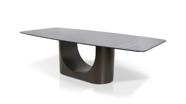 A modern dining table with a rectangular, subtly rounded tabletop and a sculptural, single pedestal base. The tabletop has a marble-like pattern with grey and white veining. The base is a dark, matte, curved structure that appears to be U-shaped when viewed from the side. — 3D model