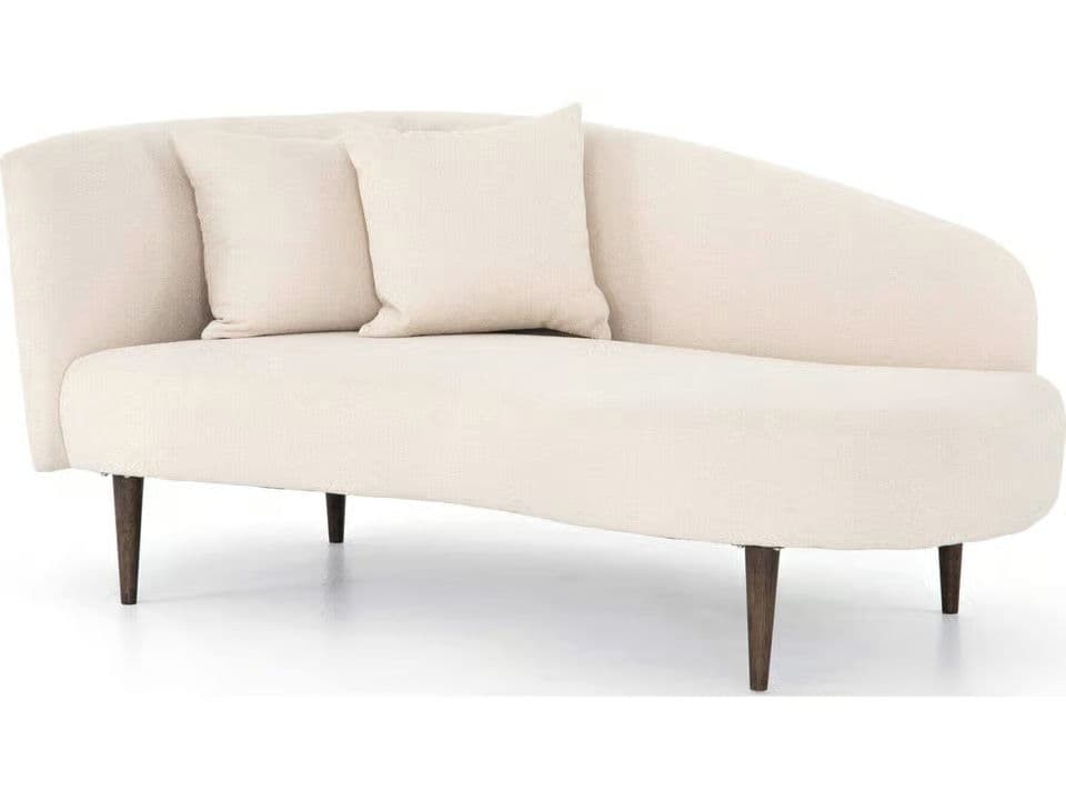 A contemporary chaise lounge upholstered in cream-colored bouclé fabric, featuring a curved backrest and tapered dark wooden legs, accompanied by two matching throw pillows. — 3D model