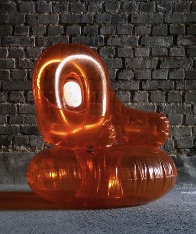 An orange, translucent inflatable armchair resembling a balloon. It has a rounded seat and a curved backrest. The surface shows creases and reflections, indicative of an inflated material. A valve is visible on the seat cushion. — 3D model