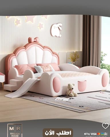 A children's bed with a pink and white scalloped headboard featuring a bow accent. The frame is predominantly white with pink accents, resembling ears or rounded protrusions on the sides. It includes a built-in slide and a small set of steps on the left side. The bedding features a pink geometric pattern. A small stuffed bear is placed on the foot of the bed. — 3D model