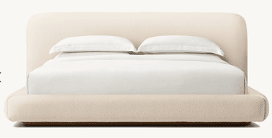 A modern platform bed featuring a fully upholstered frame and a gently rounded headboard, presented against a plain white background. The bed is covered in a light beige, textured fabric, giving it a soft and contemporary aesthetic. It is outfitted with clean white bedding, including a fitted sheet, flat sheet, and two pillows. — 3D model