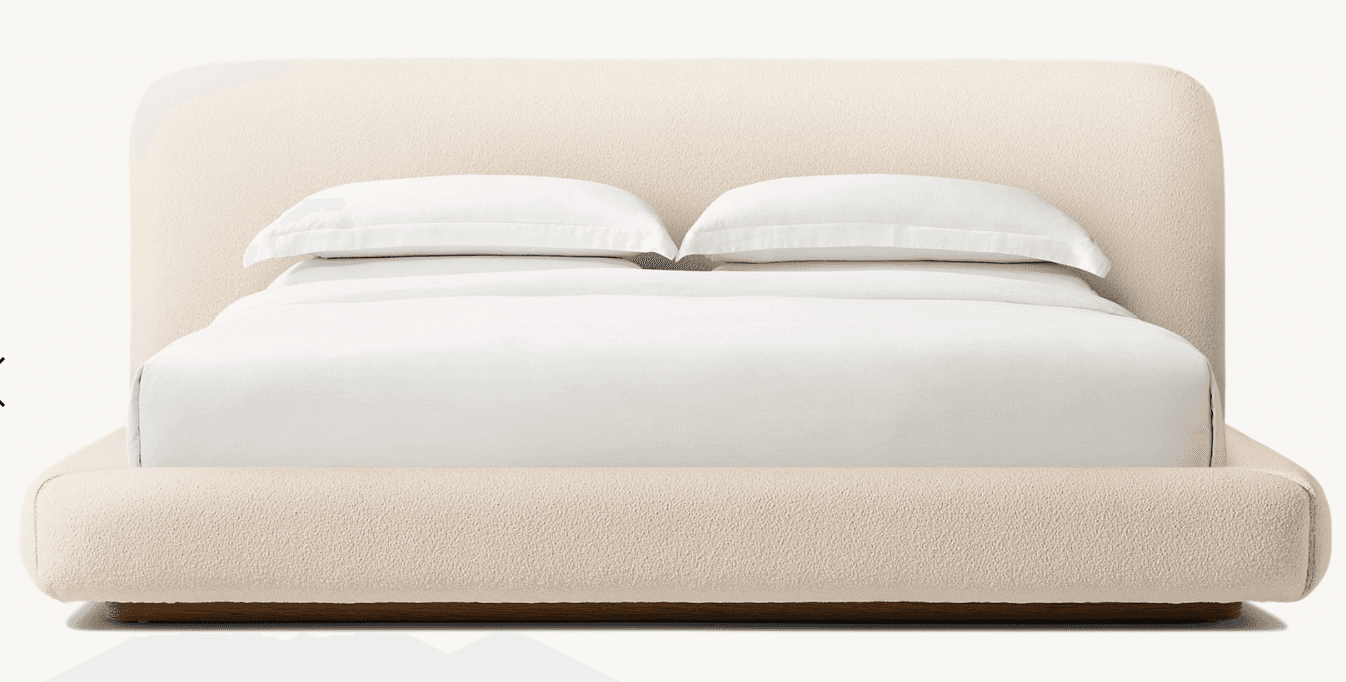 A modern platform bed featuring a fully upholstered frame and a gently rounded headboard, presented against a plain white background. The bed is covered in a light beige, textured fabric, giving it a soft and contemporary aesthetic. It is outfitted with clean white bedding, including a fitted sheet, flat sheet, and two pillows. — 3D model