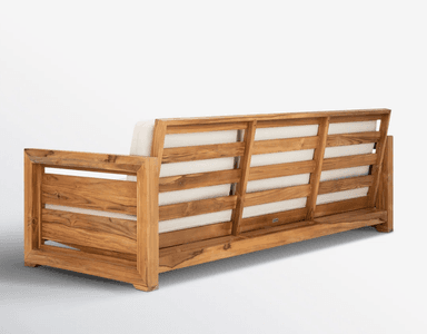 A contemporary three-seater outdoor sofa featuring a sturdy teak wood frame and three plush, off-white upholstered cushions for both the seat and backrest. The frame has a slatted design on the armrests and visible wood grain, indicating natural material and construction suitable for outdoor use. — 3D model