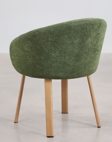 A contemporary dining armchair featuring a dark green, textured upholstered seat and back, with integrated armrests forming a continuous, rounded bucket shape. The chair is supported by four natural light-toned wooden legs that taper slightly downwards. The overall design suggests a comfortable yet minimalist aesthetic, suitable for modern interiors. — 3D model