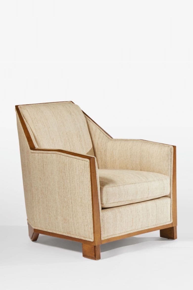 An upholstered armchair featuring a prominent exposed wooden frame along the armrests and base. The upholstery is a light, textured fabric, likely a linen or similar blend, in a cream or off-white color. The chair has a geometric, streamlined design with squared feet, indicative of early 20th-century modernism or Art Deco styles. It includes a loose seat cushion and a fixed back cushion. — 3D model