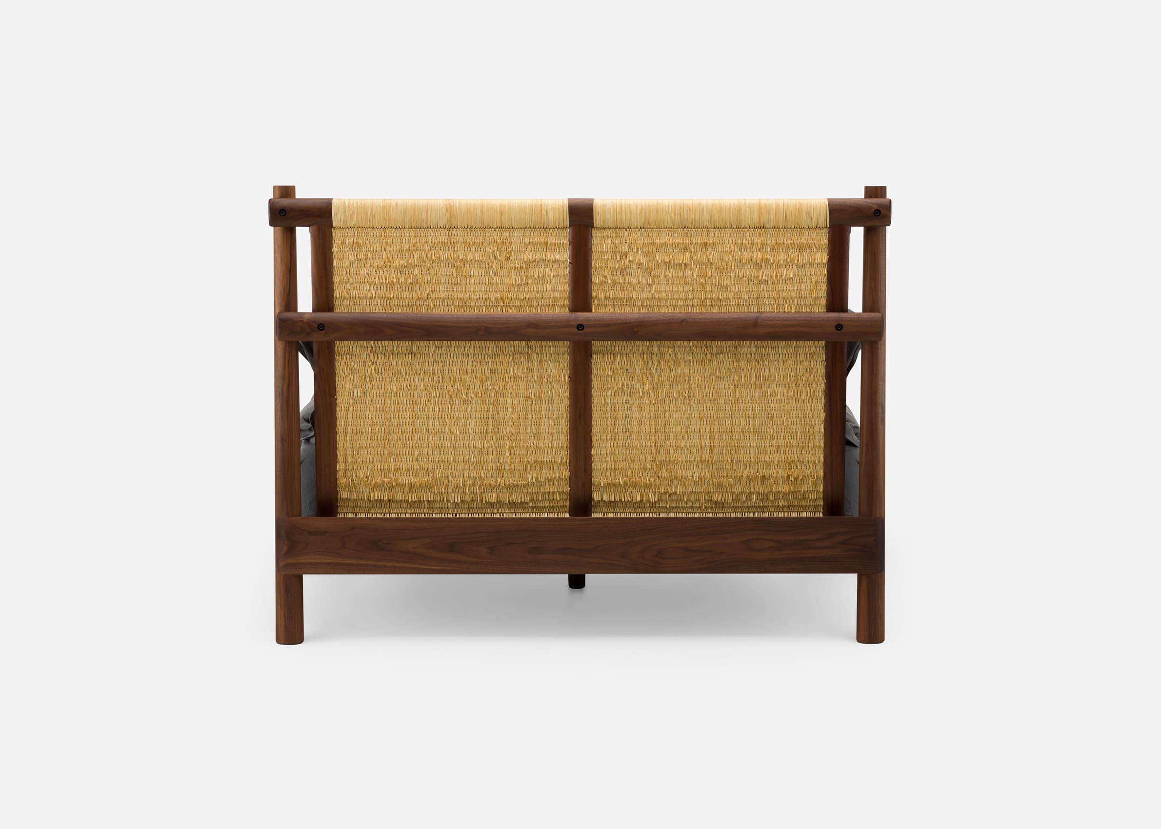 A loveseat seen from the back, featuring a dark walnut wood frame and a light-colored woven natural fiber backrest. The frame is composed of horizontal and vertical wooden members, within which two distinct woven panels are secured. A dark gray cushion is partially visible through the woven material. — 3D model