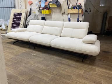 A modern, sectional sofa with a cream-colored textured fabric upholstery. It features a low profile base, distinct seat and back cushions with channel tufting, and integrated armrests. The sofa is supported by a dark wood frame and thin, black metal legs. — 3D model