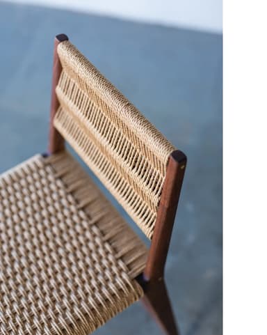 A bar stool with a wooden frame and a woven seat and backrest. The stool features four tapered legs connected by a lower stretcher for stability. The seat and backrest are constructed from a natural woven material, creating a textured surface. The wooden frame appears to be dark-stained. — 3D model