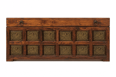 A rectangular, dark-stained wooden chest featuring a lift-top lid and decorative embossed brass panels on the front and sides. The lid is equipped with two brass ring pulls. The front facade displays twelve square brass panels arranged in a grid pattern, each with an intricate, symmetrical design. The chest rests on a short, integrated plinth base. — 3D model