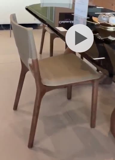 A modern dining chair featuring a light beige upholstered seat and backrest, contrasted with a warm brown wooden frame that wraps around the lower back and forms the tapered legs. The design is sleek and minimalist, with visible stitching on the upholstery. — 3D model