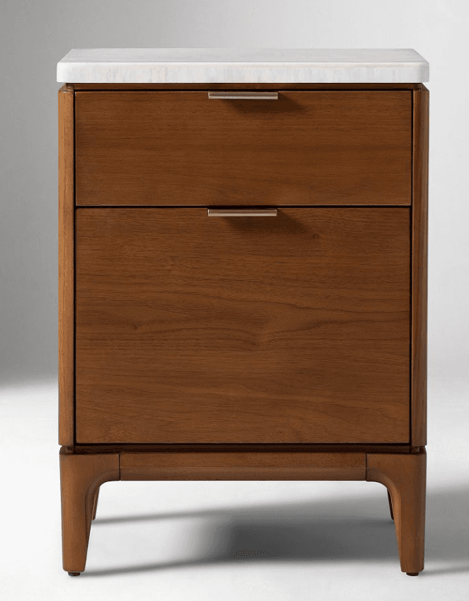 A wooden nightstand with a white top surface and two drawers. The nightstand features brass-colored drawer pulls and is supported by tapered legs. — 3D model