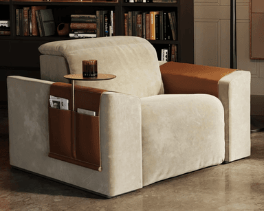 A contemporary recliner chair with a beige fabric upholstery and brown leather accents. The chair features a reclining mechanism, indicated by the extended footrest and visible mechanical components underneath. It includes integrated storage pockets on the side and a small, circular swivel table attached to a metal arm. — 3D model