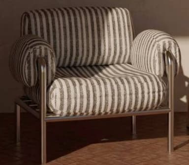 A modern armchair featuring a robust metal frame and plush, striped fabric upholstery. The chair has a square silhouette, with thick seat and back cushions, and distinctive cylindrical padded armrests that wrap around the tubular metal structure. The fabric is a neutral grey and off-white stripe pattern, complementing the matte silver finish of the metal frame. — 3D model
