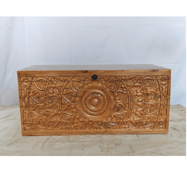 A rectangular storage chest crafted from solid wood, featuring a natural, warm brown finish with prominent wood grain and knot details. The chest has a hinged lid that sits flush when closed, and dark, possibly forged iron, pull handles are visible on the short sides. The overall design suggests a rustic or farmhouse aesthetic, emphasizing natural materials and robust construction. — 3D model