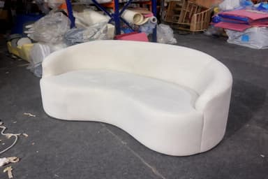 A white, curved sofa with a continuous backrest and seat, exhibiting a contemporary design. The piece has soft, rounded edges and appears to be upholstered. — 3D model